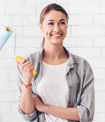 young-woman-holding-paint-roller-for-renovation-at-YVK8WJV